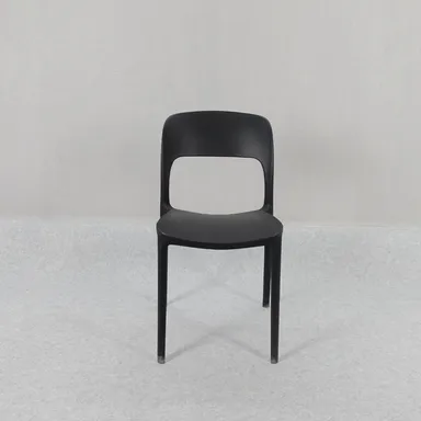 등받이 가운데가 뚫린 검은색 일체형 플라스틱 의자, 가늘게 뻗은 네 다리