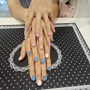 파스텔 핑크와 하늘색으로 칠한 손톱을 네일 매트 위에 올려둔 모습