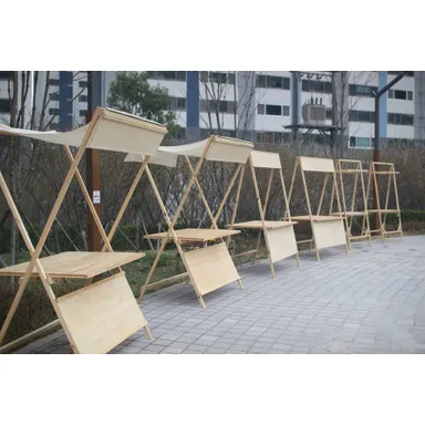 X자 목재 프레임과 천 차양, 진열 선반과 하단 가림판을 갖춘 나무 부스