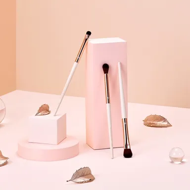 분홍빛 배경에 세워둔 메이크업 브러시 세 자루 제품 사진