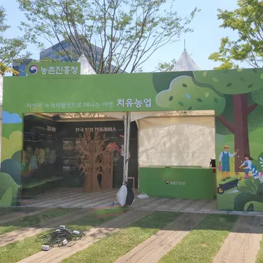 흰 몽골텐트 전면을 감싼 초록색 목공 마스크 구조물