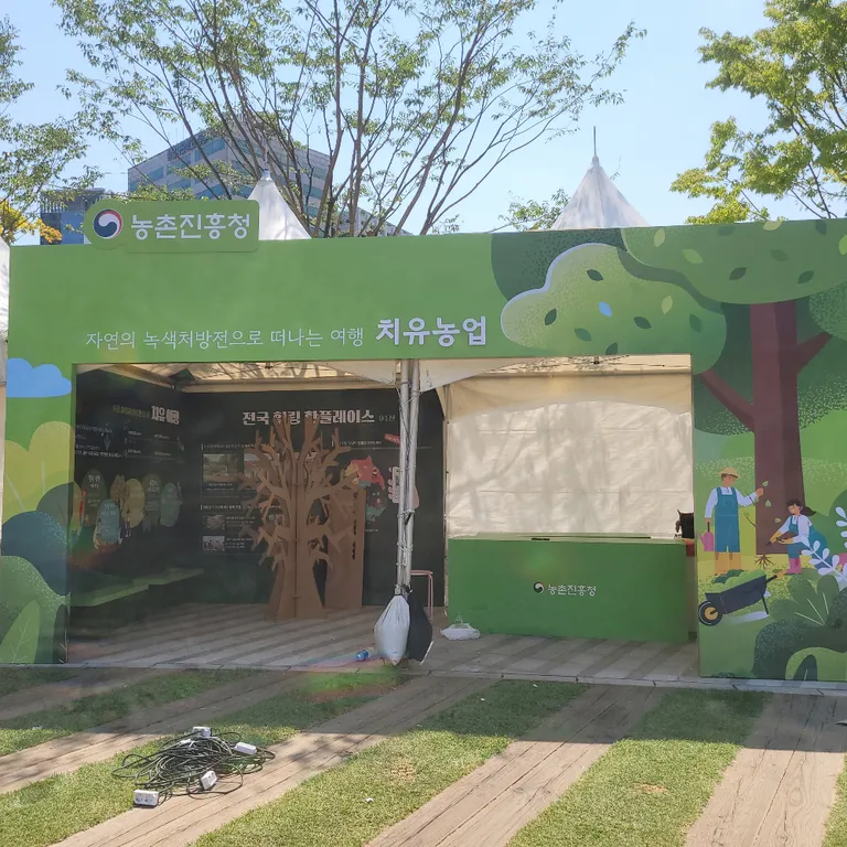 흰 몽골텐트 전면을 감싼 초록색 목공 마스크 구조물