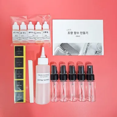 향료 병과 향수 베이스, 공병, 라벨, 시향지가 놓인 향수 만들기 체험 키트 구성