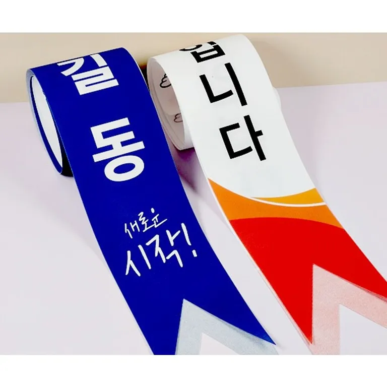 글자가 인쇄된 파란색과 흰색 행사용 어깨띠 두 장을 놓고 찍은 사진
