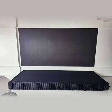 검은 스커트를 두른 조립식 무대바닥과 뒤편 백월이 함께 설치된 행사장 모습