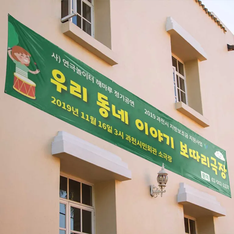 건물 외벽에 끈으로 걸어 설치한 가로형 인쇄 현수막