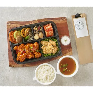 양념 깐풍기와 튀김, 반찬이 담긴 검은 칸막이 도시락과 밥·국