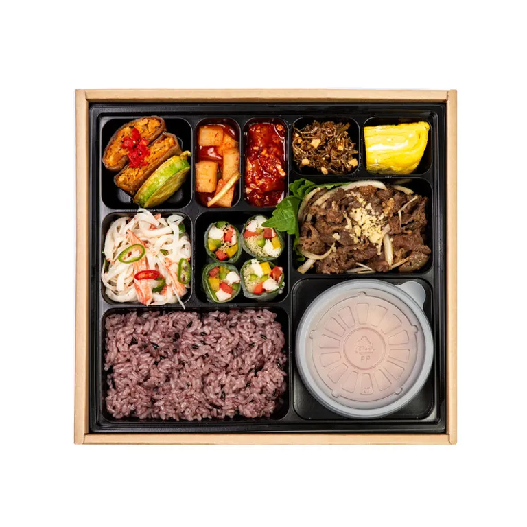 양념 소불고기와 흑미밥, 여러 찬을 담은 한식 단체 도시락