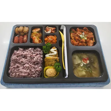제육볶음과 흑미밥, 반찬과 국이 함께 담긴 단체 행사 도시락