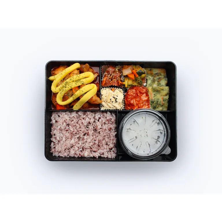 매콤한 닭갈비와 잡곡밥, 반찬, 국이 담긴 한식 정식 도시락